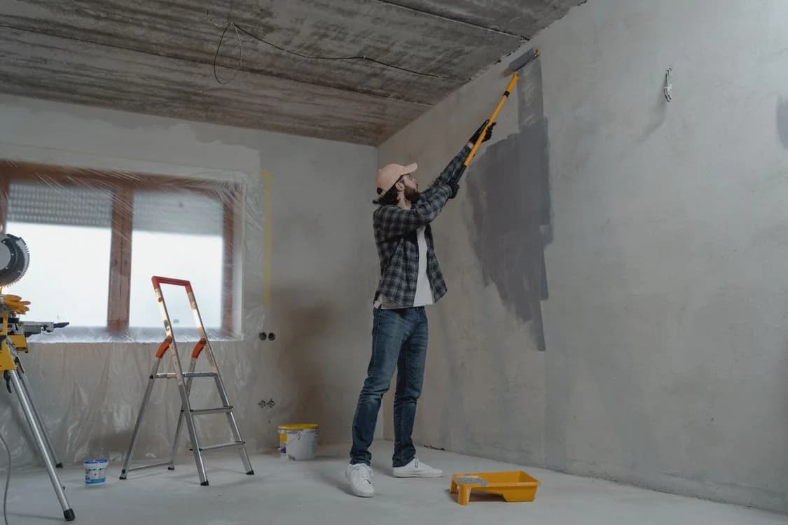En målare arbetar med roller på en innervägg
